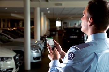 Security Guard with smartphone at a car dealership