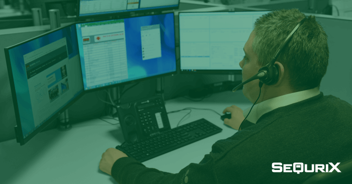 Man with headset sitting in front of three computer screens