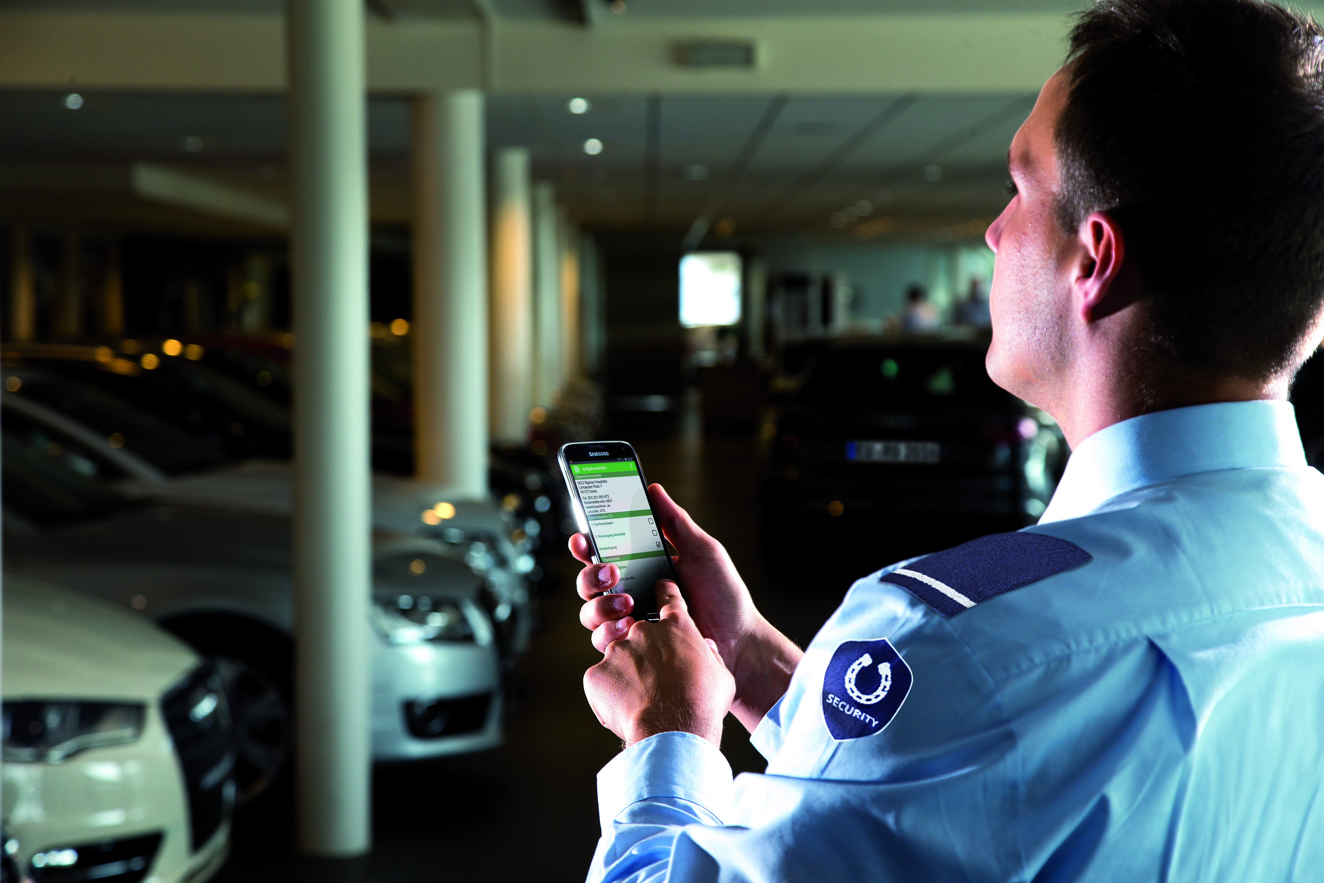 Security Guard with smartphone at a car dealership